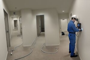 טכנאי בודק קיר במכשיר לאיתור נזילות במסדרון בניין